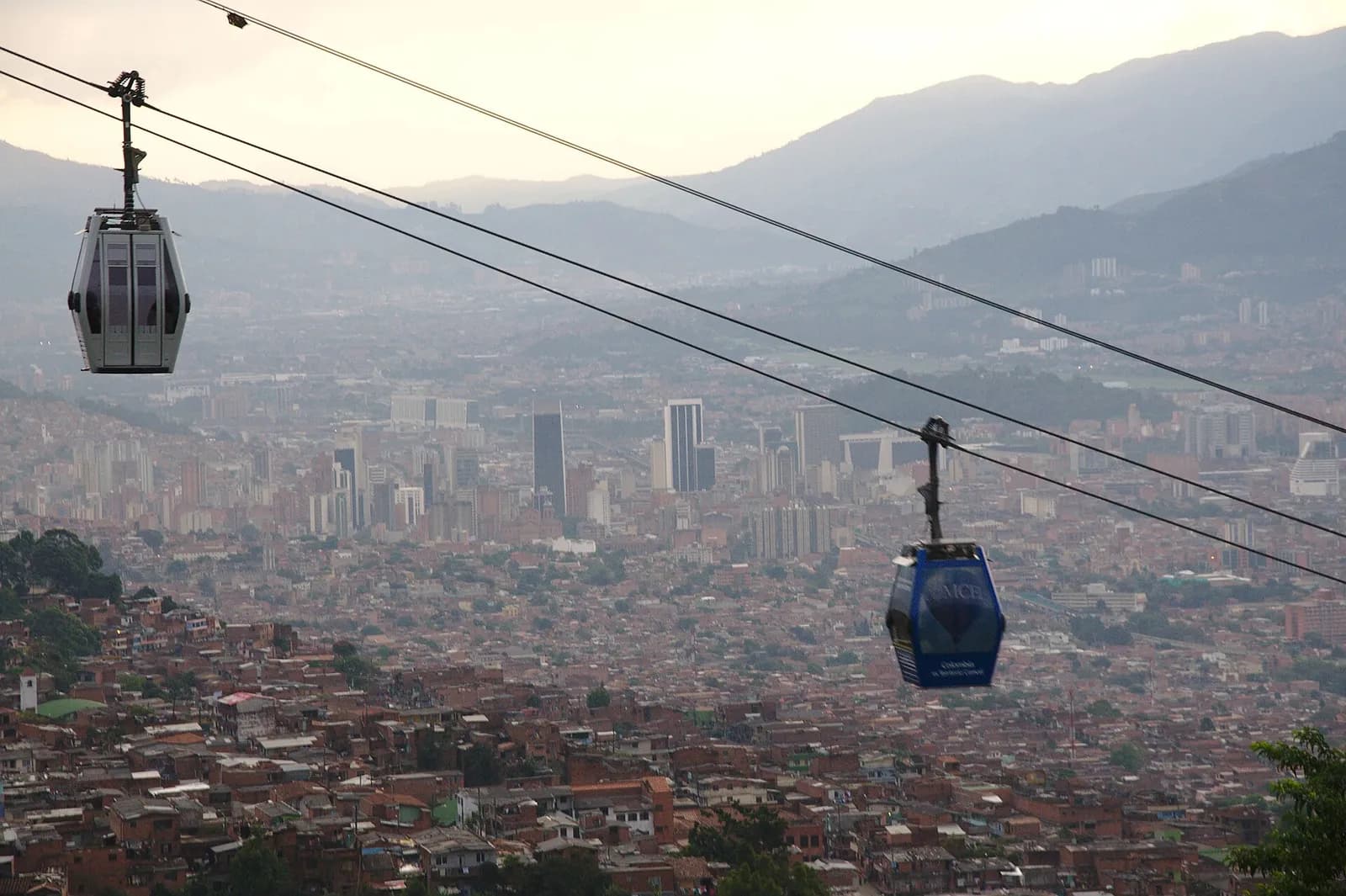 Cabinas del Metrocable sobre las laderas de Medellín con la ciudad en el valle al fondo